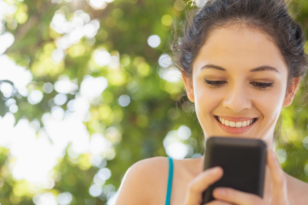 Cheerful woman texting with her smartphone